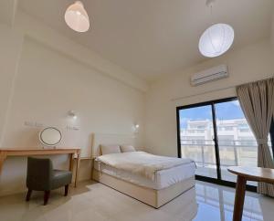 a bedroom with a bed and a desk and a window at Grass in the Wind B&B in Magong