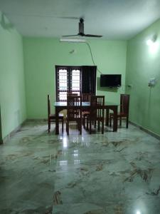a dining room with a table and chairs and a television at Bridgettine Paradise 2 in Kalpetta