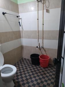 a bathroom with a toilet and buckets on the floor at Bridgettine Paradise 2 in Kalpetta