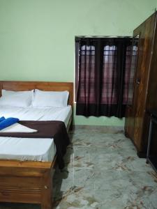 a bedroom with two beds and a window at Bridgettine Paradise 2 in Kalpetta
