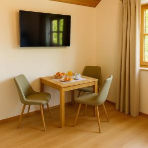 a table with four chairs and a television on the wall at Direkt am Wanderweg, Ferienwohnung im Allgäu nahe Oberstaufen in Oberstaufen