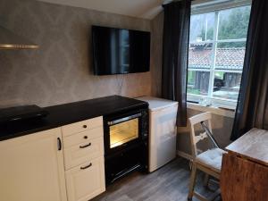 a kitchen with a stove and a tv on the wall at Cozy Fjord Studio in Åna-Sira Near Brufjell and Jøssingfjord in Flekkefjord