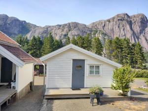 a white house with a porch with mountains in the background at Cozy Fjord Studio in Åna-Sira Near Brufjell and Jøssingfjord in Flekkefjord +26 photos