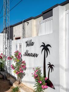 a sign on the side of a building with flowers at Villa alnaser in Awlād ‘Umar