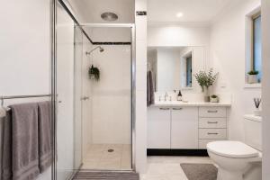 a white bathroom with a shower and a toilet at Golfside Getaway by Ready Set Stay in Rosebud