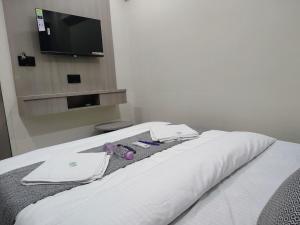 a bed with white sheets and a tv on a wall at Hotel Sky Dream in Gandhinagar