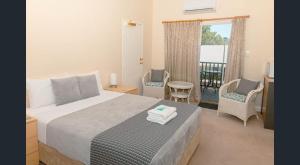 a bedroom with a bed and chairs and a balcony at Nest & Rest York in York
