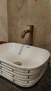 a sink with a copper faucet in a bathroom at Kanha Hotel in Kānpur