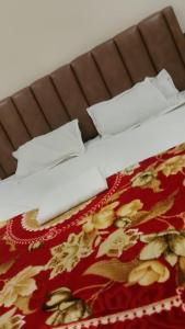 a bed with white pillows and a red blanket at Kanha Hotel in Kānpur