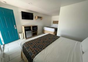 a hotel room with a bed and a tv and a door at Sun Valley Motel in Phoenix