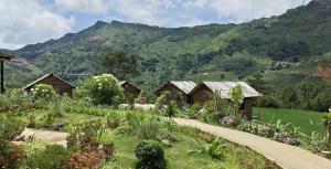 a row of wooden huts in a valley with mountains at De Mont Retreat Sapa in Sapa