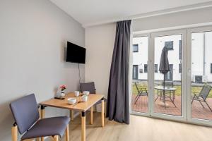 a living room with a table and chairs and a balcony at Terrasse Double Studio Apartments in Lübeck