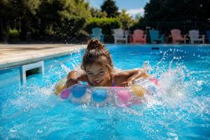 a little girl is riding on an inner tube in a swimming pool at Camping les Avenières in Manthes