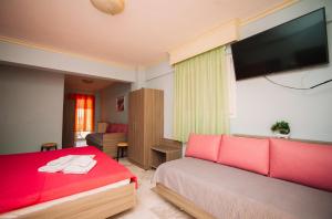 ein Schlafzimmer mit einem roten Bett und einem Flachbildfernseher in der Unterkunft Hotel White Rose Beach in Olympiakí Aktí