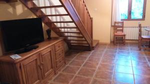 a living room with a television and a staircase at Duplex Calle El Tillo in Escarrilla