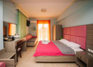 ein Schlafzimmer mit einem großen Bett und einem Schreibtisch in der Unterkunft Hotel White Rose Beach in Olympiakí Aktí