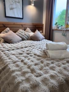 a large white bed with two pillows on it at Domek z jacuzzi Studnica 39 in Studnica +11 photos