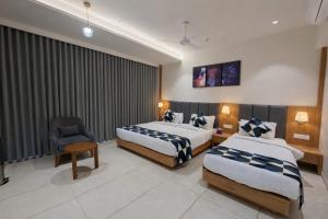 a hotel room with two beds and a chair at Hotel Premji, Dwarka in Dwarka +10 photos