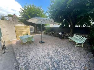 a patio with a table and an umbrella and benches at Le Puy D'Eraigne in Saint-Nectaire +3 photos