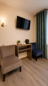 a room with a chair and a desk and a television at Baiterek Resort in Karagandy