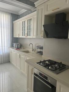a kitchen with white cabinets and a stove top oven at Light & Comfortе in Mekhrably
