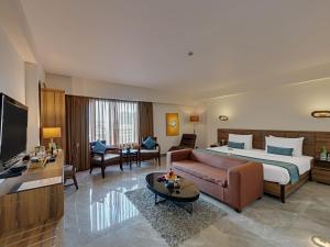 a large hotel room with a bed and a couch at Hotel Suba International Sahar Road Mumbai in Mumbai