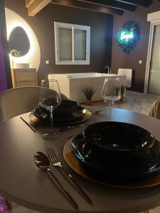 a table with a black plate and two wine glasses at Escapade in Saint-Jouin-Bruneval