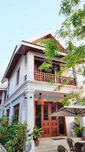a white house with an umbrella in front of it at Asoca Hotel Luang Prabang in Luang Prabang