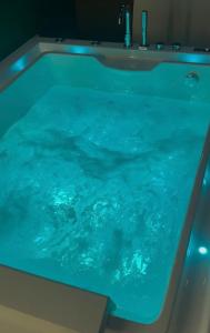 a large tub filled with blue water in a bathroom at Escapade in Saint-Jouin-Bruneval