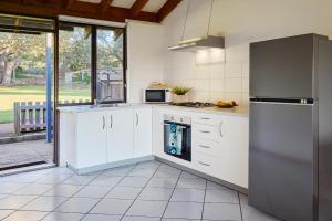 a kitchen with white cabinets and a stove top oven at Chandlers Smiths Beach Villas in Yallingup +39 photos