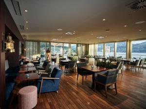 a restaurant with tables and chairs and windows at Belvédère Strandhotel in Spiez