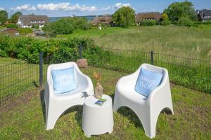 two white chairs with blue pillows sitting next to a fence at Reethaus Zickersche Berge - WG 02 mit Kamin und Terrasse in Gager