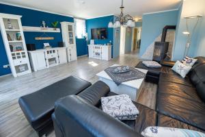 a living room with blue walls and a leather couch at Reethaus Zickersche Berge - WG 02 mit Kamin und Terrasse in Gager