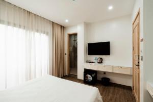 a bedroom with a white bed and a television at The Serenity Hanoi in Hanoi