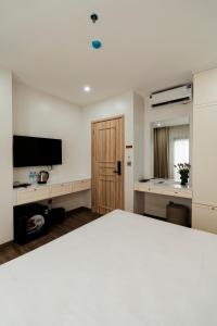 a room with a bed and a television and a door at The Serenity Hanoi in Hanoi