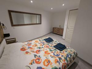 a bedroom with a bed with a floral bedspread and a mirror at La Cachette Floracoise in Florac