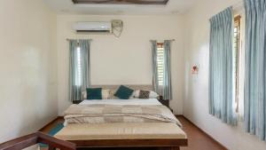 a bedroom with a bed and two windows at The Grand Villa Kochi in Cochin