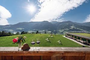 a table with wine glasses and a field with mountains at Moarlhof - Farm Nature Resort in Castelrotto