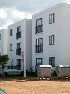 a white building with a car parked in front of it at Tatu City Serene 2BR Apartment in Tatu City