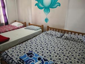 two twin beds in a room with a wall mural at First Alleppey homestay in Alleppey