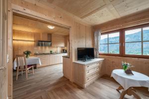 a kitchen in a log cabin with a tv and a table at Moarlhof - Farm Nature Resort in Castelrotto