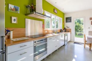 a kitchen with white cabinets and green walls at Maison Au Petit Bonheur in Argenton-sur-Creuse
