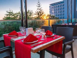 a table with red napkins and wine glasses on a balcony at Arora Hotel in Kuşadası