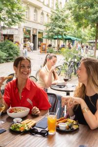 a group of women sitting at a table eating food at BOMA easy living hotel By Stay Collection in Strasbourg