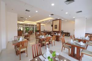 an empty restaurant with wooden tables and chairs at Grand Orchid Hotel Solo in Solo