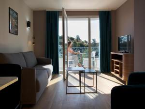 a living room with a woman looking out the window at Suite in Premier Thermal Spa Resort in Châtel-Guyon