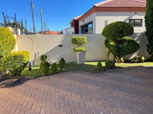 a garden with bushes and trees in front of a house at Olive Exclusive in Gaborone