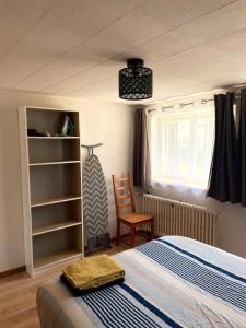 a bedroom with a bed and a chair and a window at Le repaire de l'horloger in Maîche