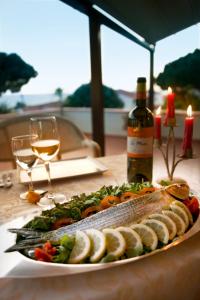 a plate of fish on a table with a bottle of wine at Hotel Corallo in Pomonte
