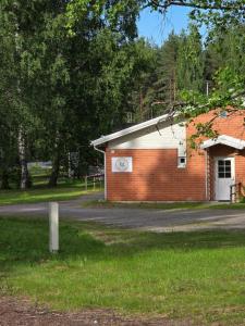 a brick building next to a road with trees at Hostelli Havumaja in Puumala